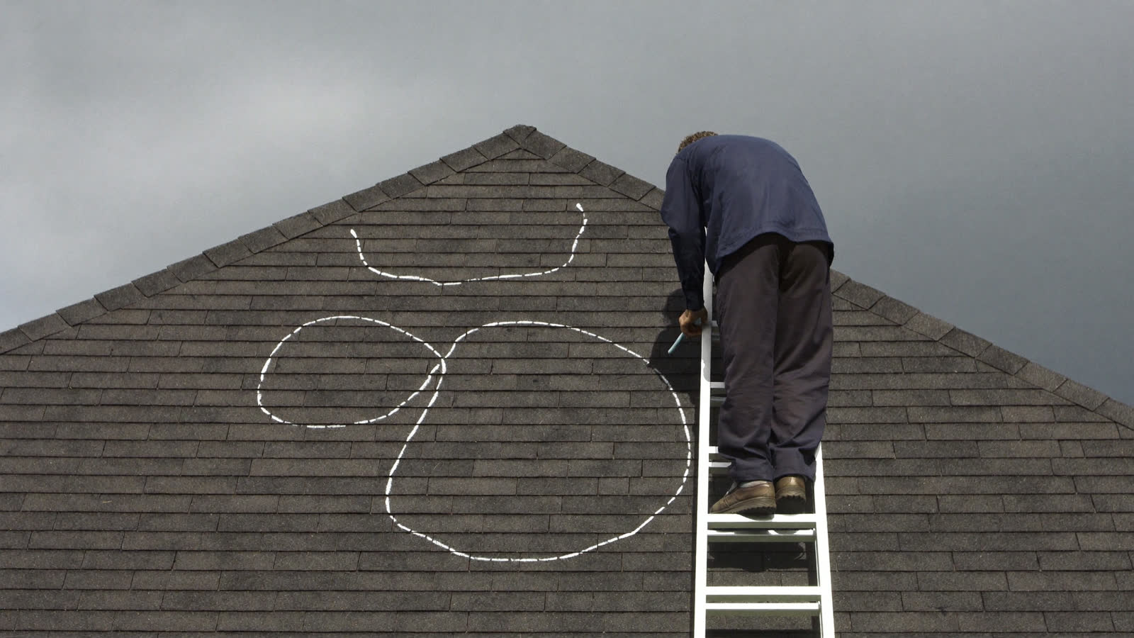 Inspector chalk-marking hail damage on an asphalt shingle roof